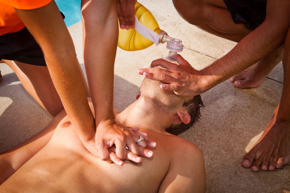 Two lifeguards giving cardiopulmonary resuscitation (CPR) to a d